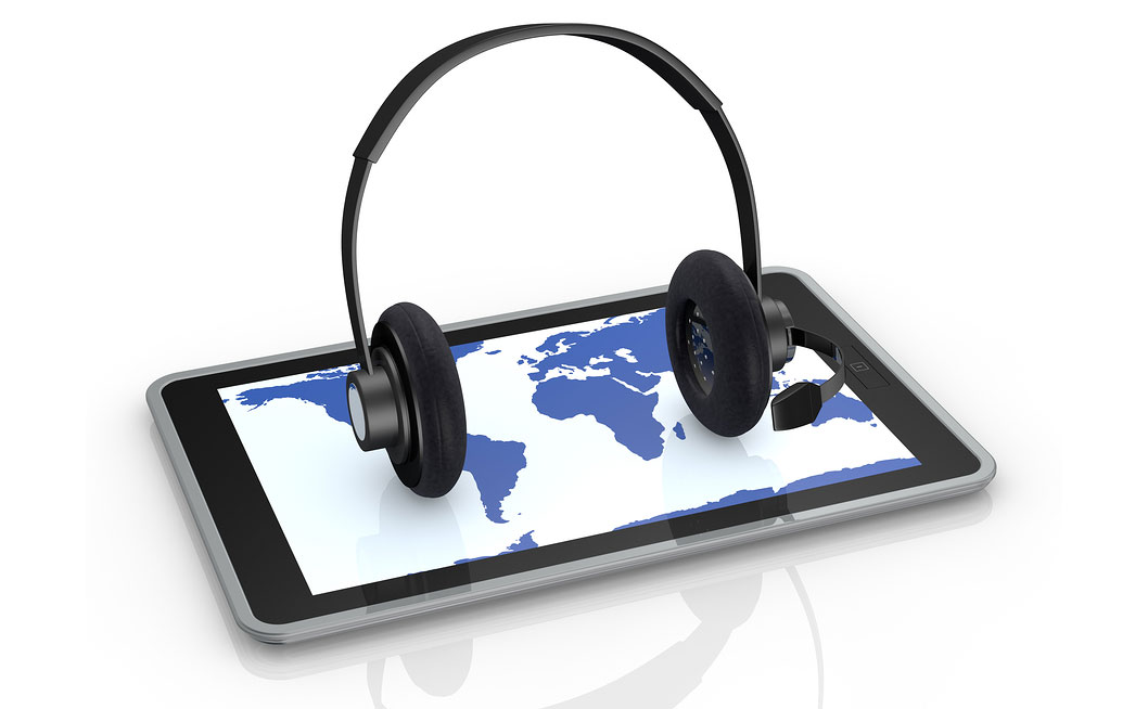 A pair of headphones resting on a computer device with a world map symbolizing multilingual transcription services.
